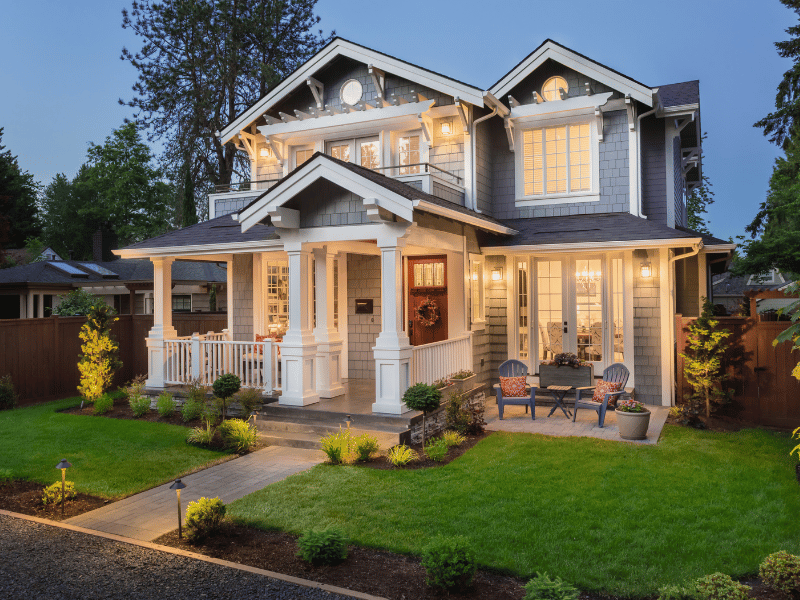 Professional front yard landscaping for a Boston craftsman home featuring a lush green lawn, a stone paver walkway with integrated path lighting, and neatly mulched garden beds.