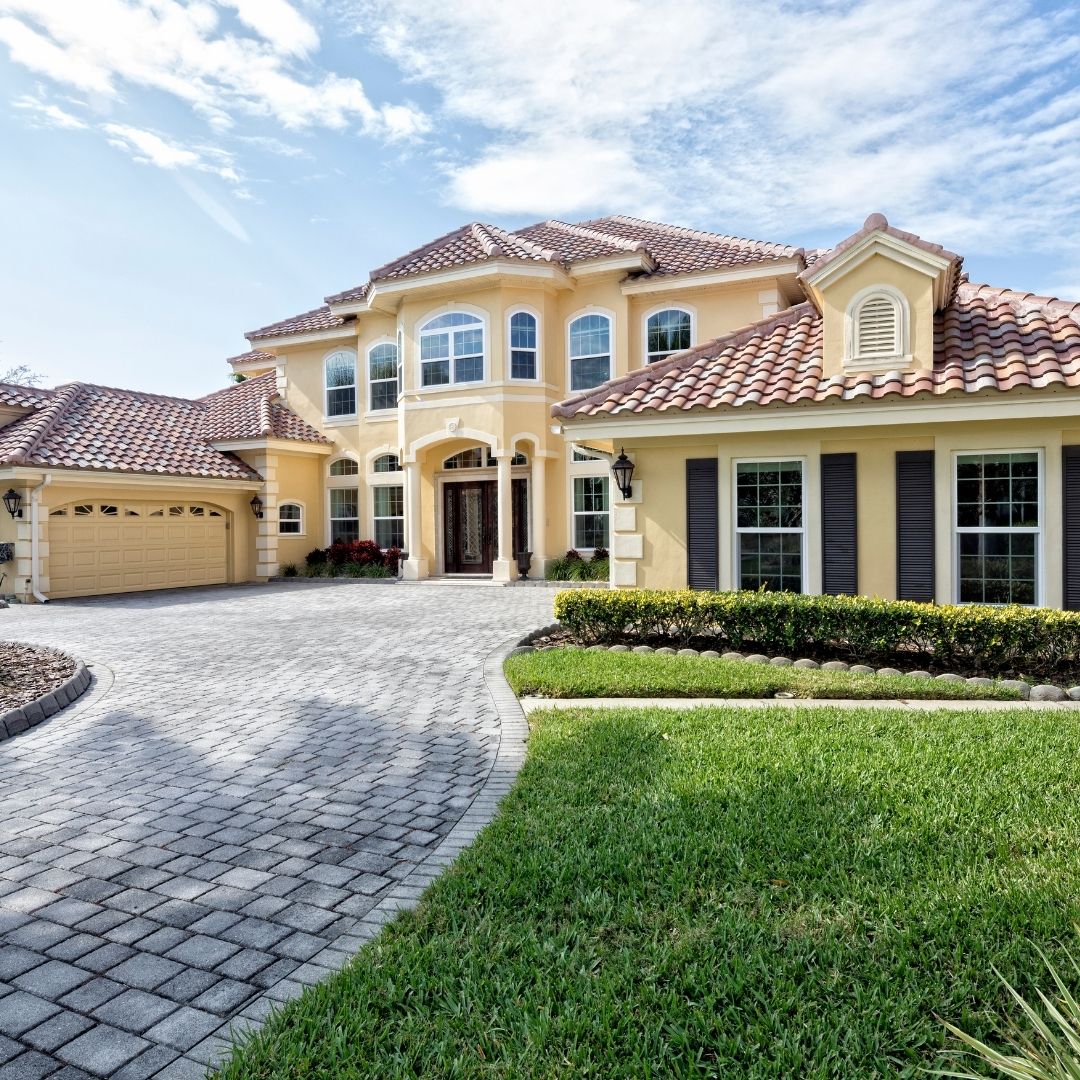 Custom interlocking stone paver driveway installation for a luxury estate, featuring a curved design and matching stone borders.