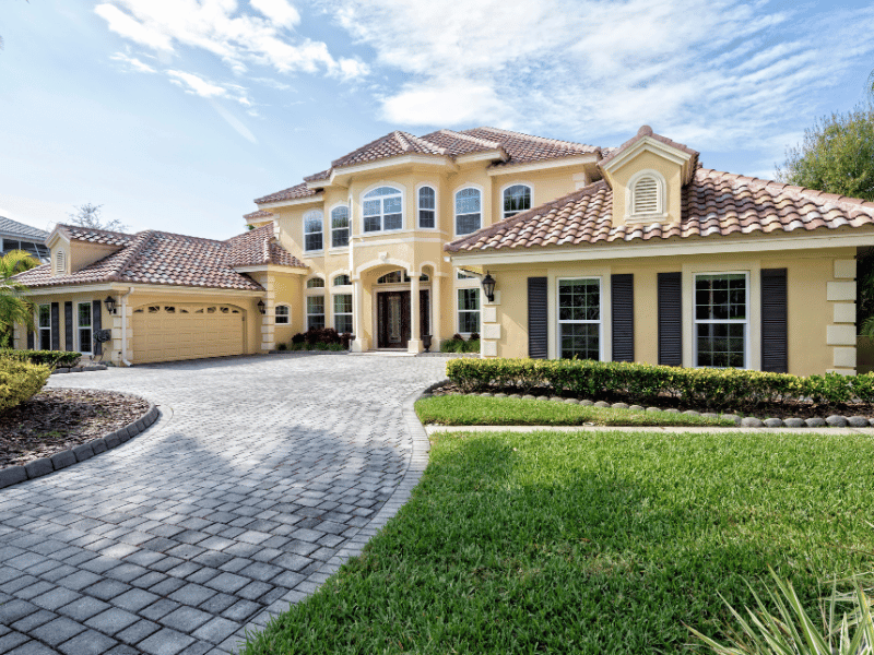 Custom interlocking stone paver driveway installation for a luxury estate, featuring a curved design and matching stone borders.