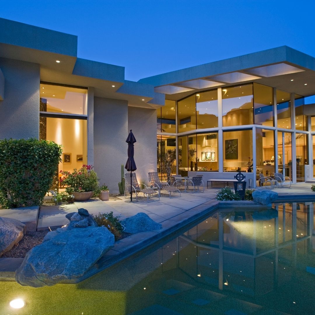 Modern luxury pool design in Boston featuring a custom stone patio, integrated natural rock features, and a seamless transition from the home's architecture to the outdoor living space.